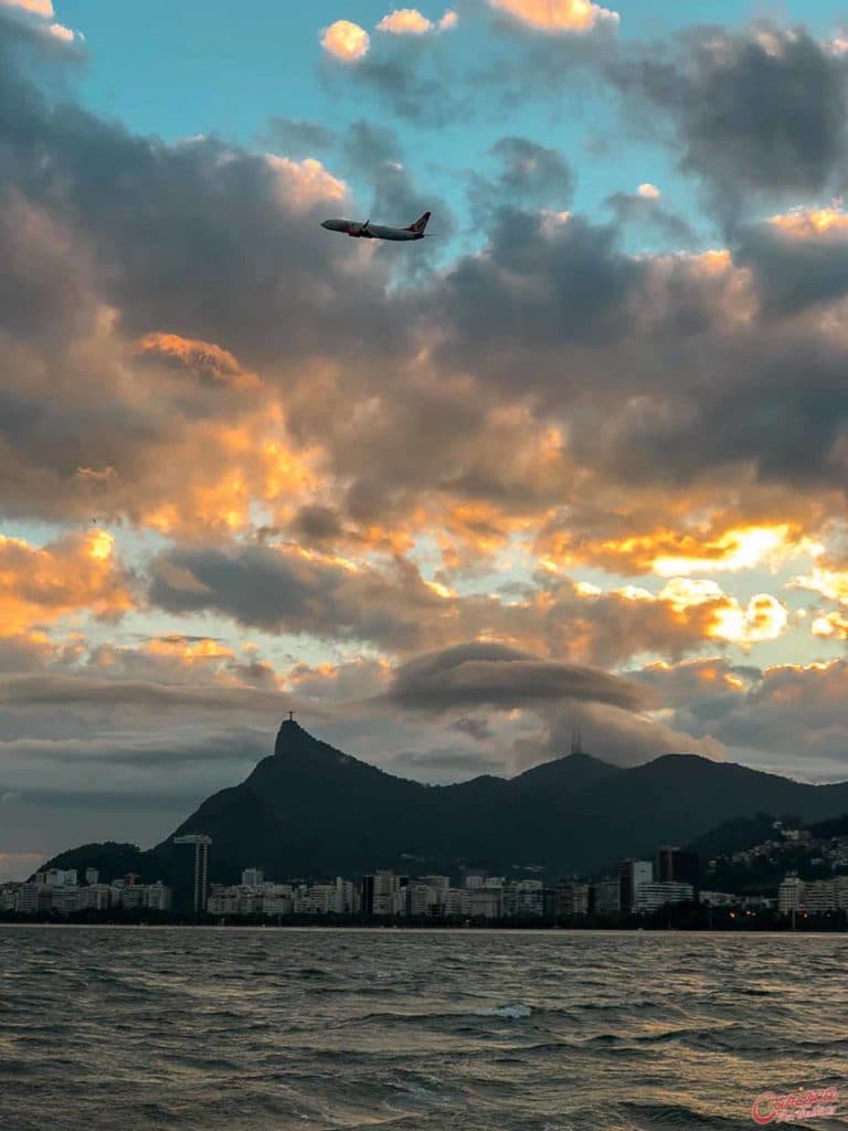 Vista para o Cristo Redentor e para um avião decolando no passeio de barco no Rio de Janeiro