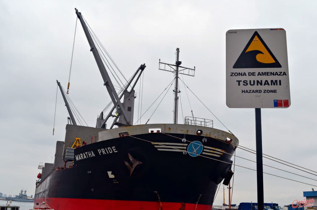 Navio no Porto de Valparaiso no Chile e placa de Tsunami